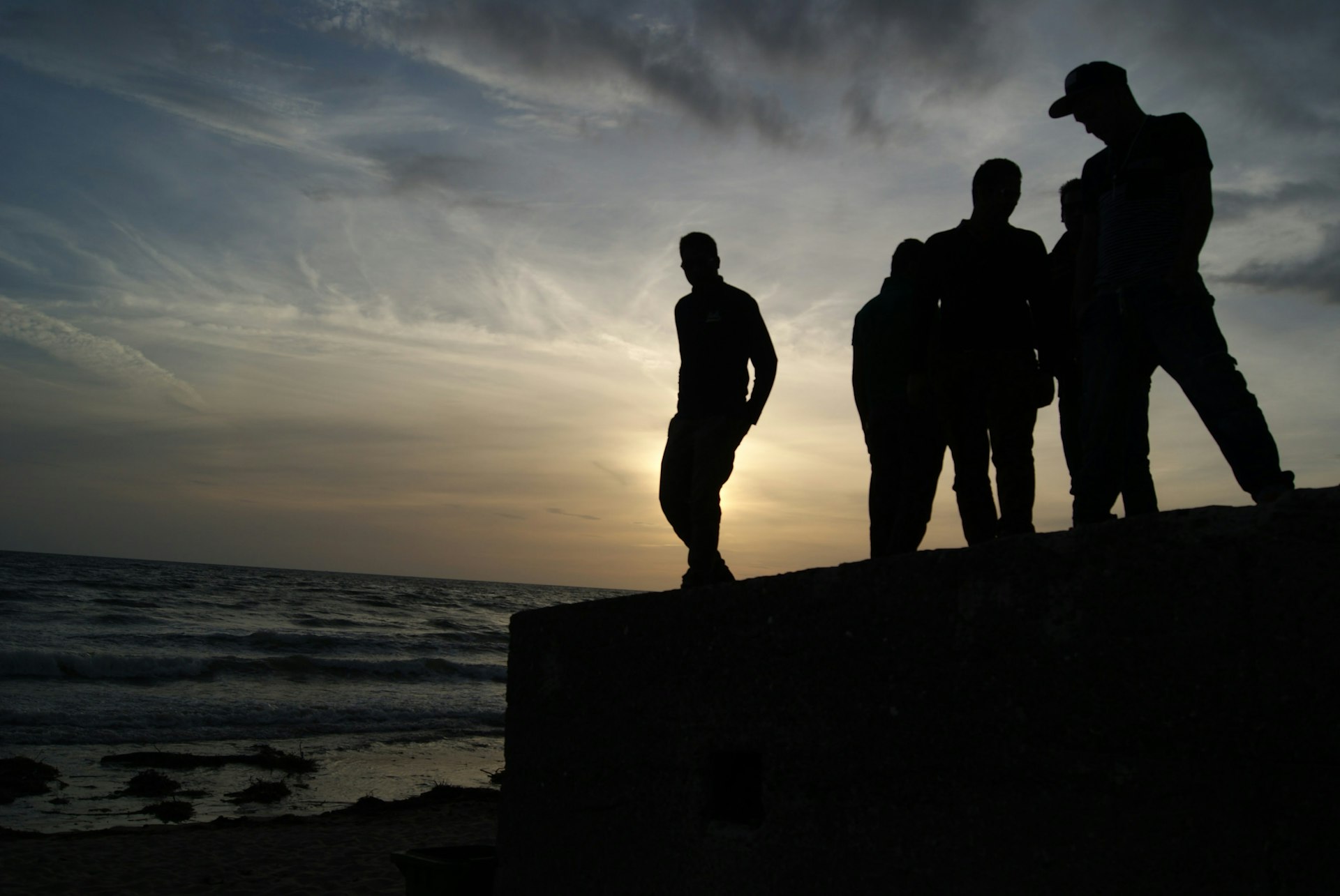 a group of people standing on top of a beach next to the ocean